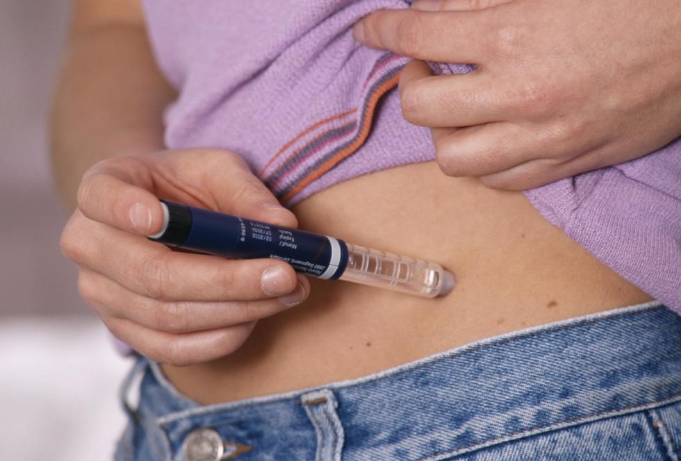 A woman gives herself an insulin injection