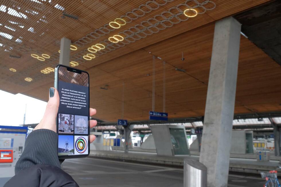 Bettina Meier-Bickel holding a mobile phone playing "Artspotting"