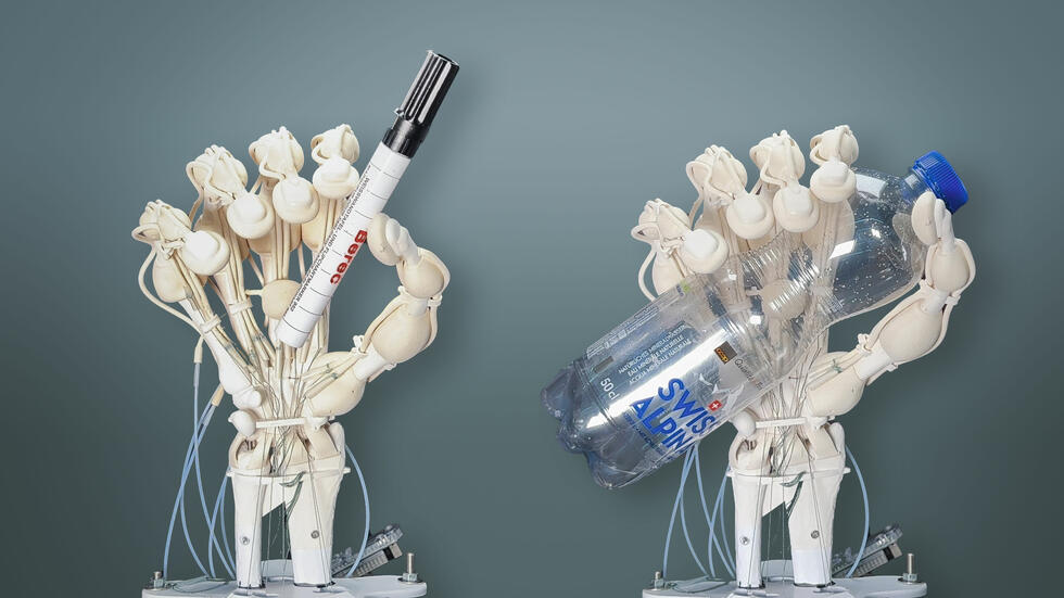 3D printed hand robots holding a pen and a bottle