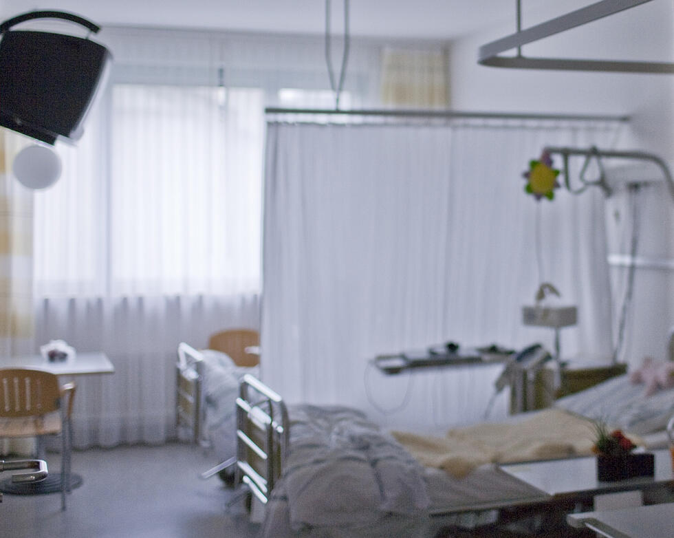 A hospital room with two beds divided by a curtain