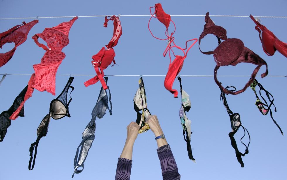 Hand grabs a bra hanging on a leash.