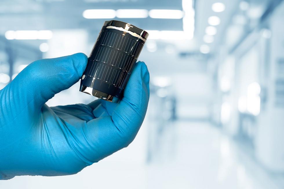 Hand with blue gloves holding flexible solar cell