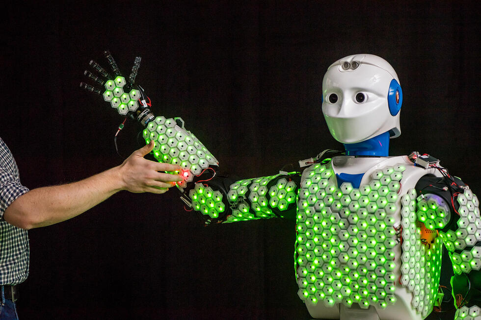 A hand touching the arm of a robot