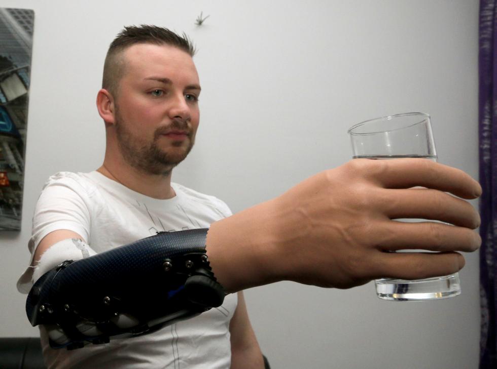 Man holding a glass and is using his hand prosteses with eye control