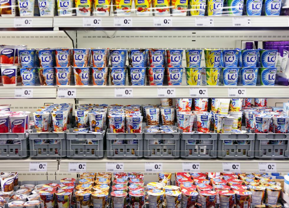 A shelf full of various yogurts at a supermarket